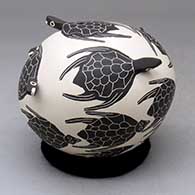 A black on buff seed pot decorated with turtle head appliques and a swimming turtles design
 by Efren Ledezma of Mata Ortiz and Casas Grandes