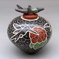 A polychrome jar decorated with a sgraffito and painted hummingbird, flower and geometric design with a hummingbird on the lid
 by Vidal Corona of Mata Ortiz and Casas Grandes