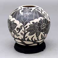 A black on white jar decorated with a sgraffito bat, flower, vine and leaf design
 by Diana Loya of Mata Ortiz and Casas Grandes
