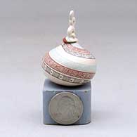 A lidded miniature polychrome jar decorated with a serpent, fineline and geometric design, click or tap to see a larger version