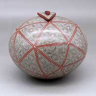 A polychrome seed pot with a triangular lid with an inlaid stone, all decorated with a spiral fineline and geometric design, click or tap to see a larger version