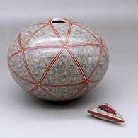 A polychrome seed pot with a triangular lid with an inlaid stone, all decorated with a spiral fineline and geometric design, click or tap to see a larger version