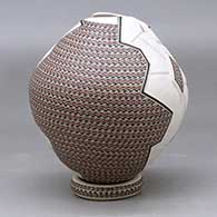 A polychrome jar with a geometric cut opening and decorated with a lightly carved, sgraffito and painted geometric design, with a custom matching stand, click or tap to see a larger version