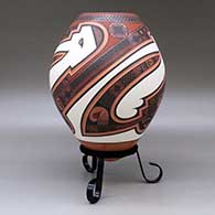 A polychrome jar decorated with a three panel lightly carved and painted sickle, bird element and geometric design, click or tap to see a larger version