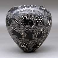 A black on white jar decorated with a sgraffito wildlife and mesh design, click or tap to see a larger version