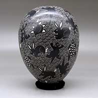 A black on white jar decorated with a sgraffito wildlife and mesh design, click or tap to see a larger version