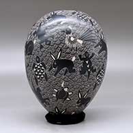 A black on white jar decorated with a sgraffito wildlife and mesh design, click or tap to see a larger version