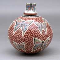 A polychrome jar decorated with a sgraffito and painted butterfly, mesh and geometric design, with a butterfly on the lid, click or tap to see a larger version