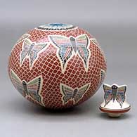 A polychrome jar decorated with a sgraffito and painted butterfly, mesh and geometric design, with a butterfly on the lid, click or tap to see a larger version