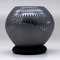 A black jar with a four panel sgraffito and painted geometric design, click or tap to see a larger version