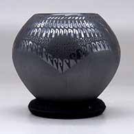 A black jar with a four panel sgraffito and painted geometric design, click or tap to see a larger version