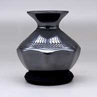 A black on black jar with an octagonal base, a rolled lip and decorated with a feather and lace geometric design, click or tap to see a larger version