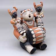 Click for a larger view A sitting grandfather storyteller figure with a drum in his lap and two children wearing deer dancer costumes on his shoulders
 by Louis Naranjo of Cochiti