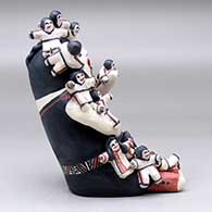 A sitting grandmother storyteller figure with fifteen children on her, click or tap to see a larger version