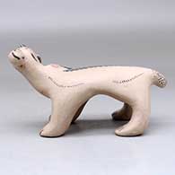 A polychrome bear figure with a fish in its mouth and decorated with a feather applique and geometric design, click or tap to see a larger version