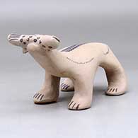 A polychrome bear figure with a fish in its mouth and decorated with a feather applique and geometric design, click or tap to see a larger version