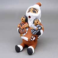 A Santa Claus storyteller figure with two children and wrapped gifts
 by Felicia Fragua of Jemez