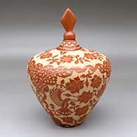 A lidded red jar decorated with a three-panel sgraffito hummingbird, flower and geometric design
 by Alvina Yepa of Jemez