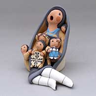 A sitting grandmother storyteller figure wearing a manta and with five children
 by Diane Lucero of Jemez