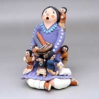 A sitting grandmother storyteller figure with five children, a sheep and a welcome basket
 by Mary Lucero of Jemez