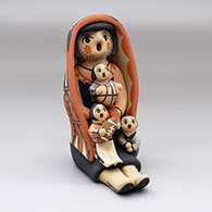 A sitting grandmother storyteller figure wearing a manta with three children
 by Chrislyn Fragua of Jemez