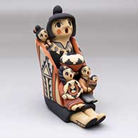 A sitting grandmother storyteller figure with a manta and four children
 by Chrislyn Fragua of Jemez