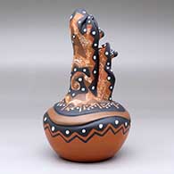 A polychrome mudhead storyteller with two children on top of a carved and painted jar, click or tap to see a larger version