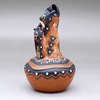 A polychrome mudhead storyteller with two children on top of a carved and painted jar, click or tap to see a larger version