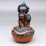 A polychrome mudhead storyteller with two children on top of a carved and painted jar
 by Felicia Fragua of Jemez