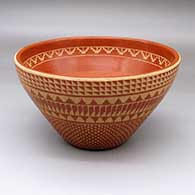 An open red bowl decorated with bands of sgraffito feathers, kiva steps, snowflakes and geometric designs
 by Wilma Baca Tosa of Jemez