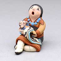 A miniature sitting grandmother storyteller with one child in a blanket
 by Mary Lucero of Jemez