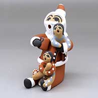 A sitting Santa Claus storyteller with 2 children, a gift, a baseball bat and a baseball
 by Felicia Fragua of Jemez