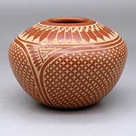 A red jar decorated with a sgraffito snowflake, feather and geometric design
 by Wilma Baca Tosa of Jemez