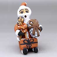 A sitting Santa Claus storyteller holding gifts and two children
 by Felicia Fragua of Jemez