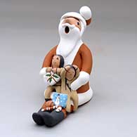 A sitting Santa Claus storyteller figure with two children and gifts
 by Diane Lucero of Jemez