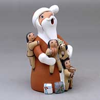 A standing Santa Claus storyteller figure with three children, a puppy and some gifts
 by Diane Lucero of Jemez