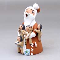 A standing Santa Claus storyteller figure with four children, a candy cane, some balls and gifts
 by Diane Lucero of Jemez