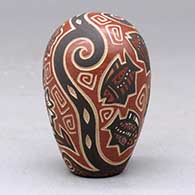 A polychrome seed pot decorated with a lightly carved and painted fish, sun, flower and geometric design, click or tap to see a larger version
