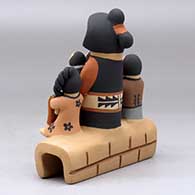A grandmother storyteller figure with four children sitting on a stone wall, click or tap to see a larger version