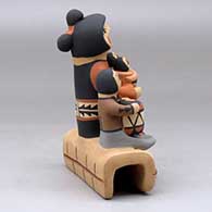 A grandmother storyteller figure with four children sitting on a stone wall, click or tap to see a larger version