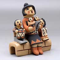 A grandmother storyteller figure with four children sitting on a stone wall, click or tap to see a larger version