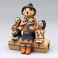 A grandmother storyteller figure with four children sitting on a stone wall
 by Chrislyn Fragua of Jemez