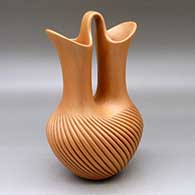 A golden micaceous wedding vase with a swirl carved melon base
 by Laura Gachupin of Jemez