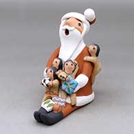 A sitting Santa Claus storyteller figure with four children and gifts
 by Diane Lucero of Jemez