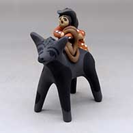 A polychrome figure of two children with a rope and blanket riding on the back of a dark horse
 by Felicia Fragua of Jemez