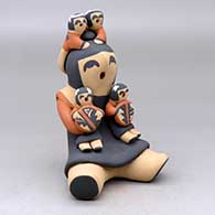A sitting grandmother storyteller figure with four children on her
 by Vernida Toya of Jemez