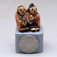 A miniature grandmother and grandfather storyteller figure wearing a manta  with two children and a drum
 by Chrislyn Fragua of Jemez
