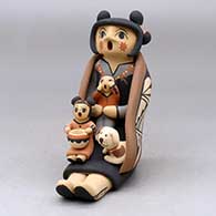 A sitting grandmother storyteller figure wearing a manta with two children, a puppy and a pot
 by Chrislyn Fragua of Jemez