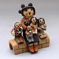 A grandmother storyteller with five children sitting on a stone wall
 by Chrislyn Fragua of Jemez