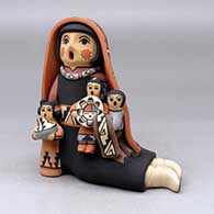 A sitting grandmother storyteller wearing a manta with three children, a pot, a welcome basket and a blanket
 by Linda Lucero Fragua of Jemez